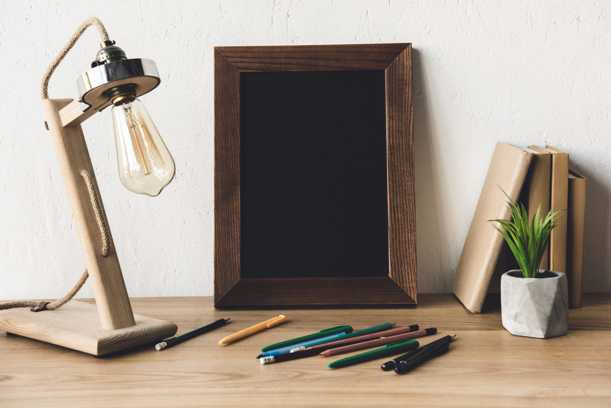 close up view of empty photo frame, table lamp and office supplies on table